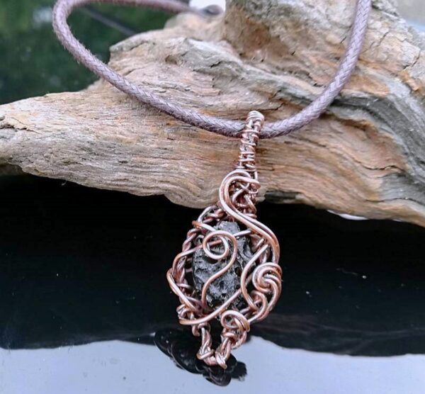 dark green moldavite stone in curls and swirls of copper wire. a unisex pendant necklace