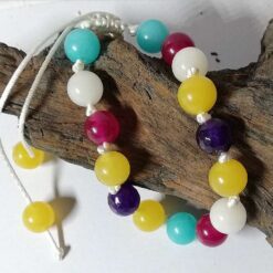 bracelet made from blue, purple, yellow, white and magenta gemstones on white knotted cord with sliding knot.