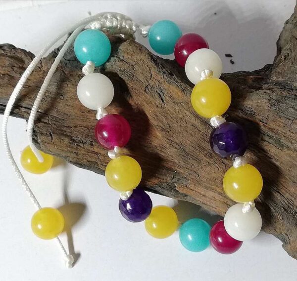 bracelet made from blue, purple, yellow, white and magenta gemstones on white knotted cord with sliding knot.