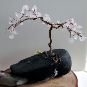 Rose Quartz stones twisted into wire and fashioned into a mini tree of life sculpture. Tree on a stone sitting on a circle of wood.