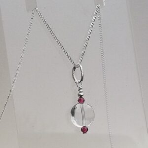 clear quartz with red garnet stone above and below. Pendant style drop necklace
