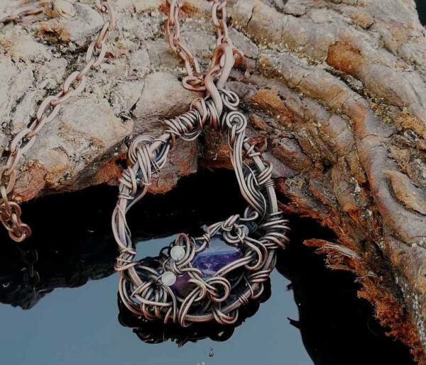 purple stone in copper wire with small white stones. pendant necklace on chain.